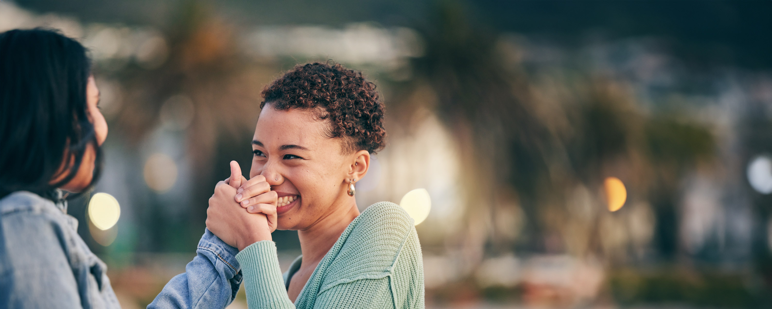 Two young adults clasping hands as they look at each other and laugh