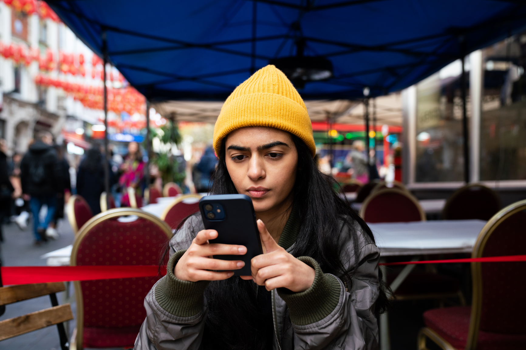 Person using smartphone at restaurant terrace.