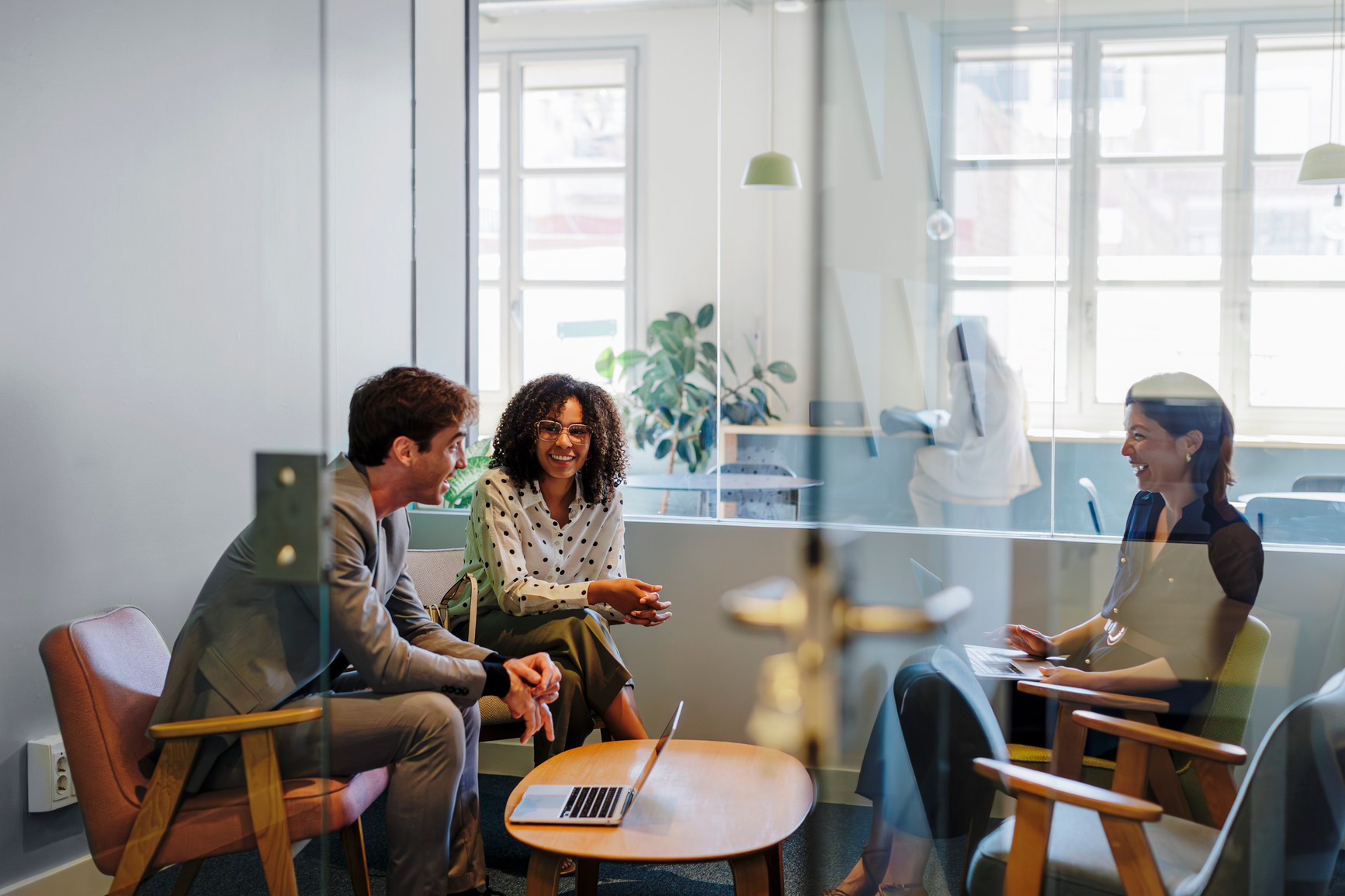 Three coworkers around a small table in a meeting room