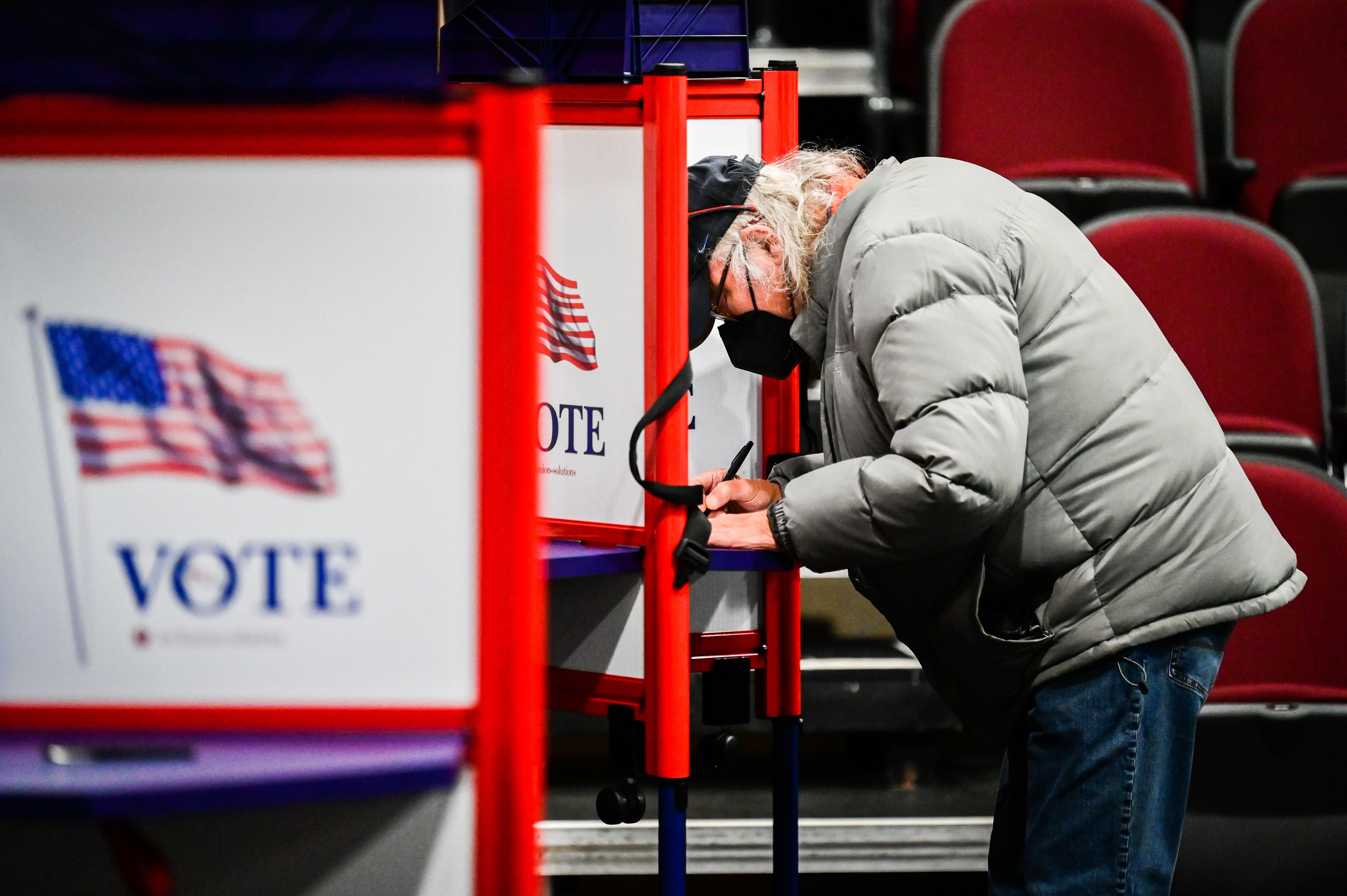 An older man casts his vote at a voting booth