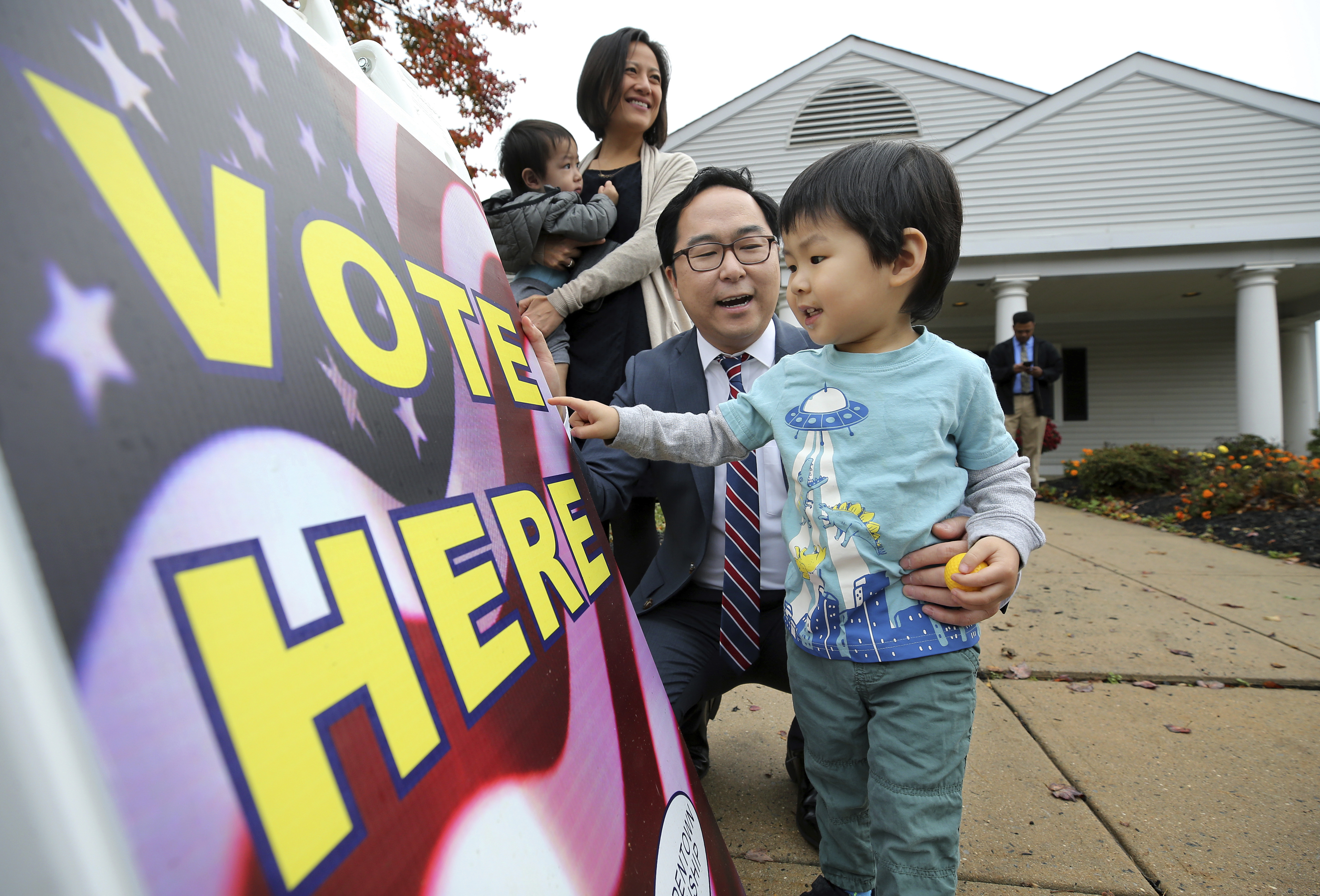 Asian family in front of a Vote Here sign