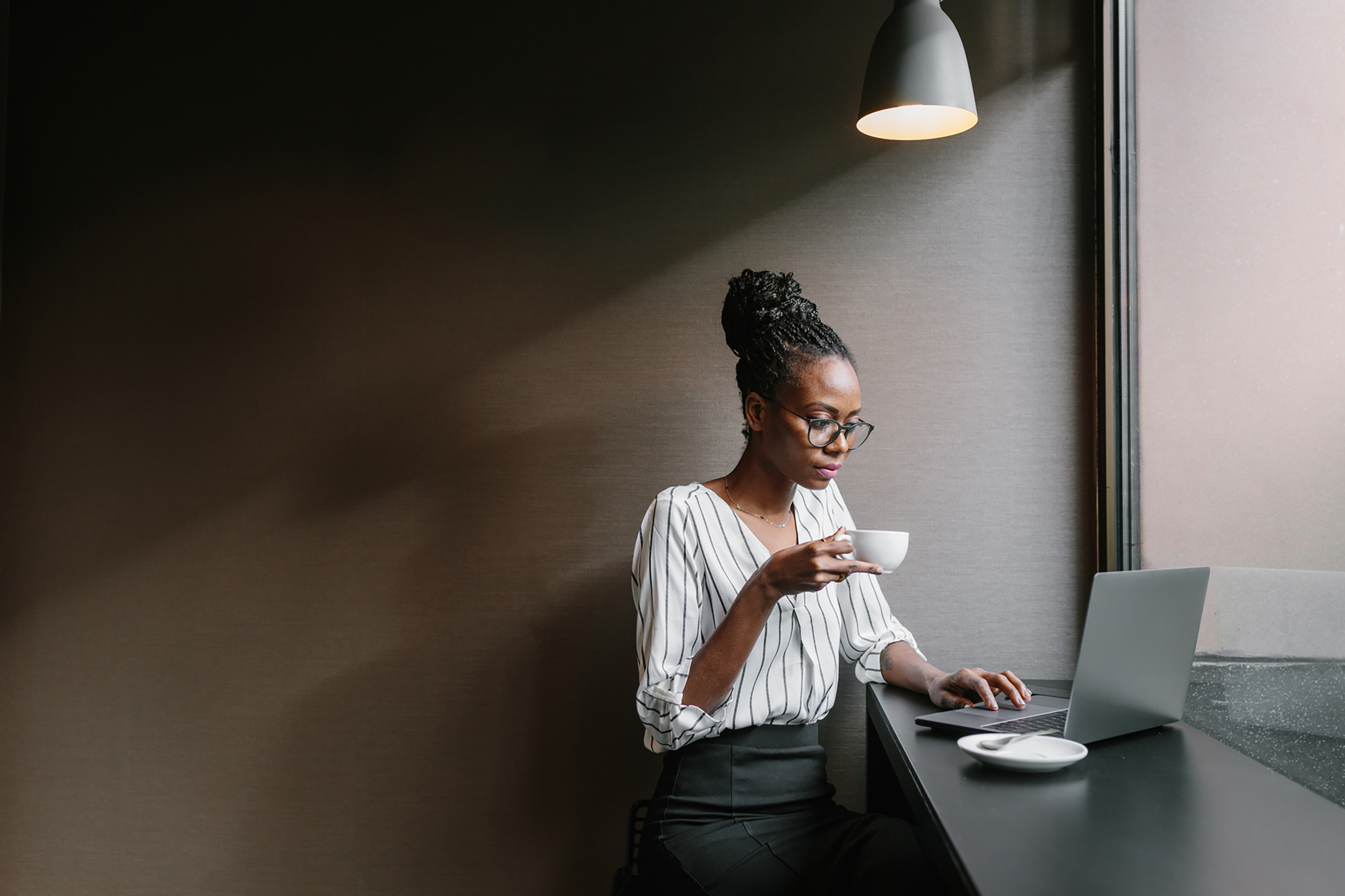 Woman holding a mug while looking at a laptop