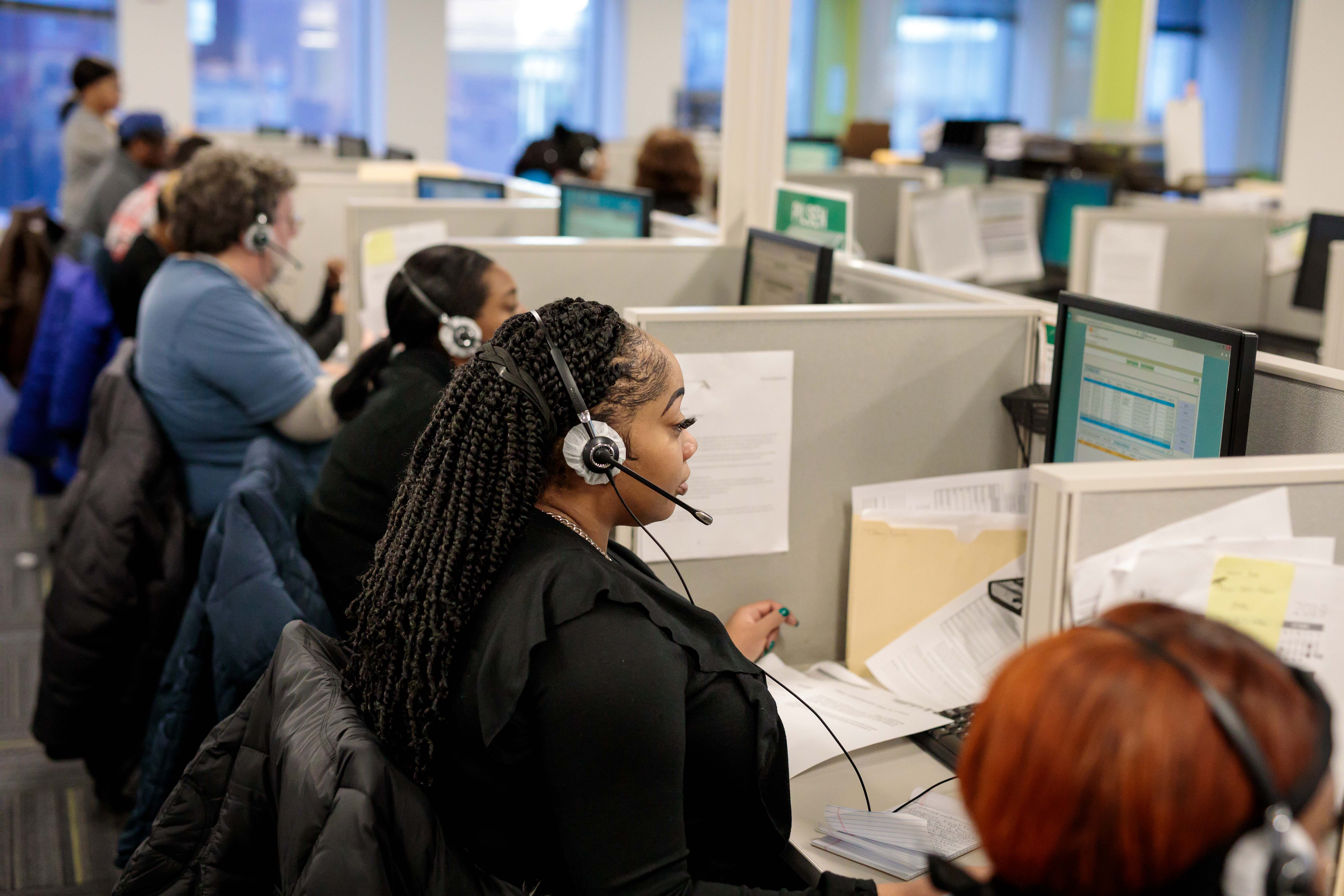 Woman sitting at a desk working on a laptop while talking on a headset