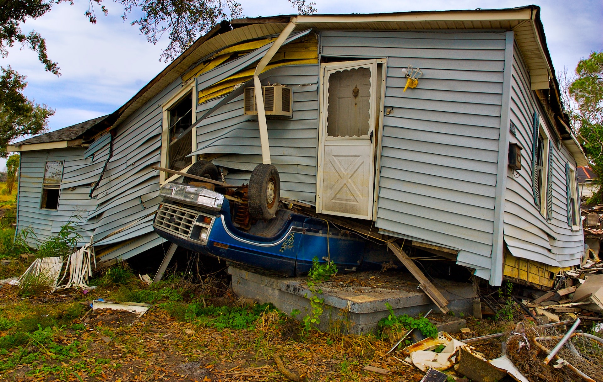 A building which appears to have been damaged by extreme weather sits on top of an upturned car