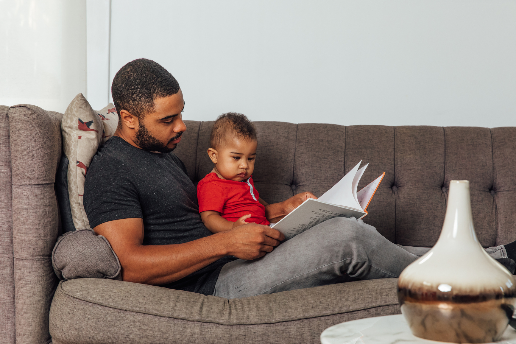 Father reading to his son on the couch.