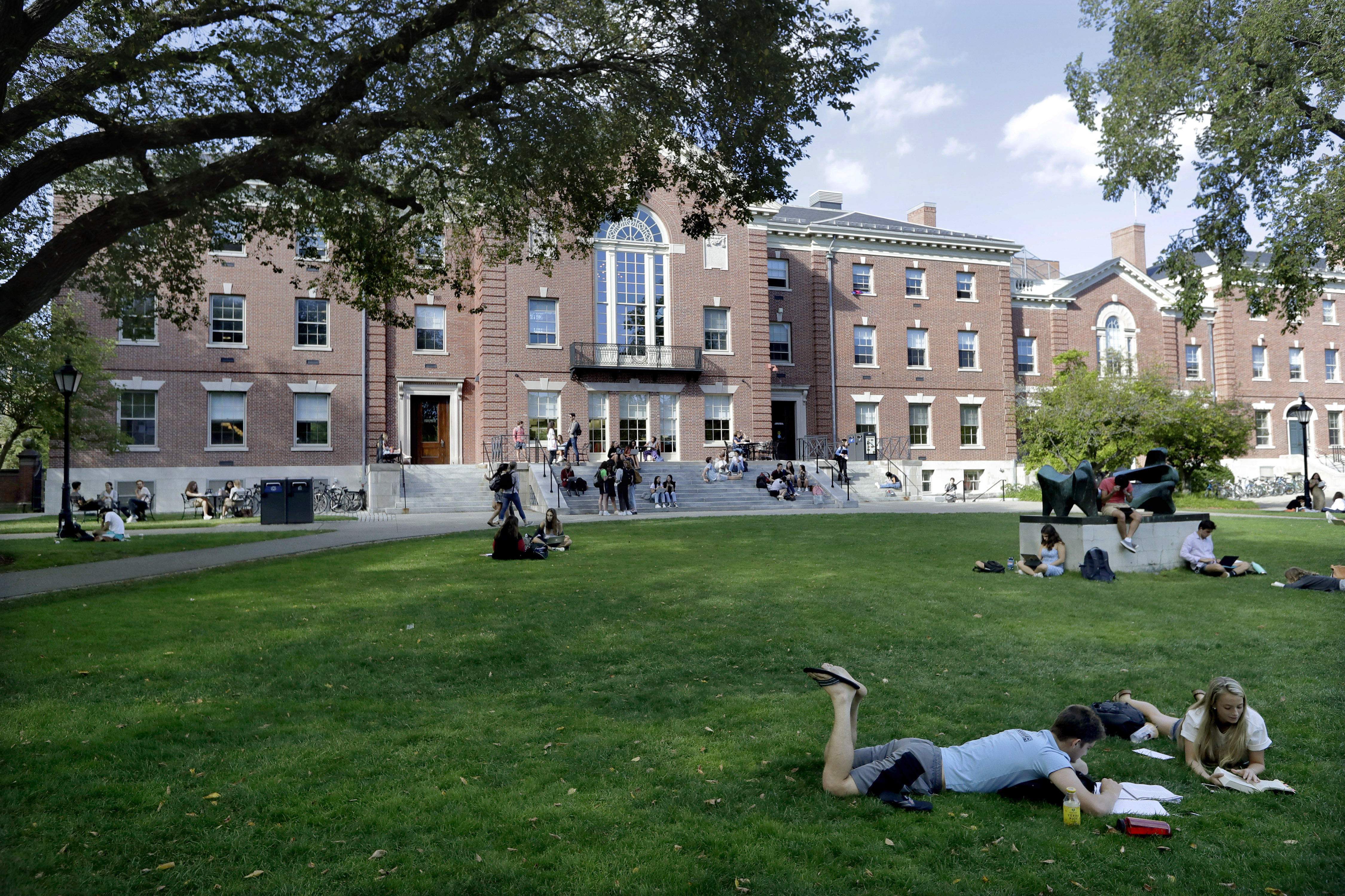 FILE - In this Sept. 25, 2019, file photo, people rest on grass while reading at Brown University in Providence, R.I. The university and attorneys for student-athletes, who challenged the Ivy League school's decision to reduce several women's varsity sports teams to club status, announced a proposed settlement Thursday, Sept. 17, 2020. (AP Photo/Steven Senne, File)