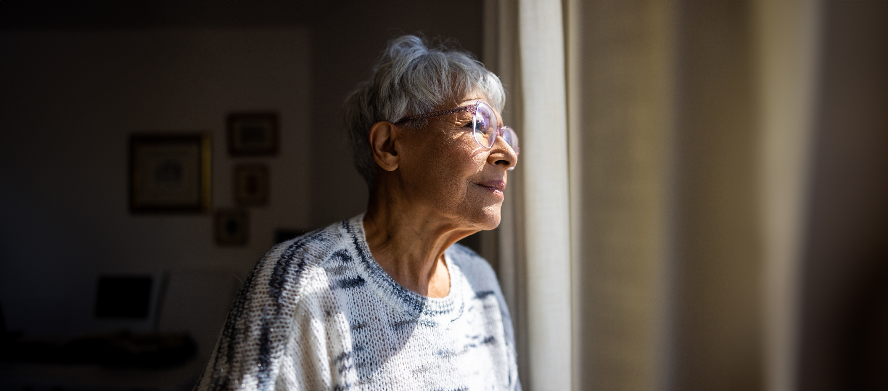 An older woman looks out a window